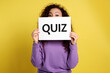 African American woman holding sign with word QUIZ on yellow background