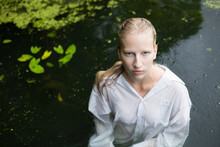 Blonde Teenage Girl In Pond With Water Lilies And Green Algae