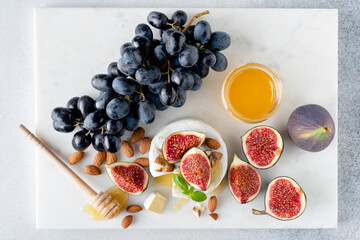 Wall Mural - Camembert cheese platter with figs, grapes, nuts and honey. Marble background, top view