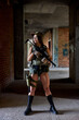 © Roman - sportive military woman with rifle with an optical sight. Army female with weapon in abandoned building, posing, looking at side, defender in military wear gear alone. military forces concept