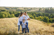 © Andrii - family with small children posing in nature on a background of tall grass and canvas
