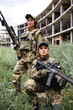 © Roman - Two young ladies friends in camouflage holding guns weapon rifle before war fight , posing at camera, looking confidently. Caucasian ladies in military gear are ready to shoot, protect the world