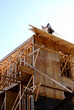 Carpenter installing plywood sheathing over roof framing