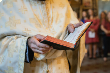 close up on midsection of the orthodox priest holding the holy bible book during the wedding or bapt