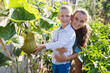 © JackF - Portrait of young woman with son working in vegetable garden checking rich harvest of pumpkins