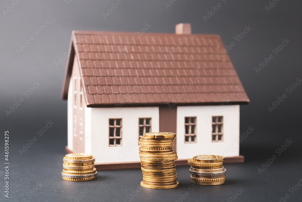Model of house with coins on dark background