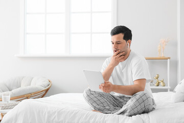 Poster - Surprised young man with tablet computer and earphones in bedroom