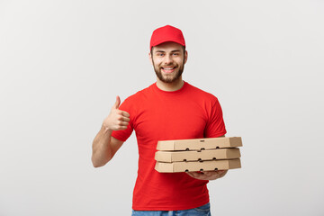 Wall Mural - Pizza delivery concept. Young handsome delivery man showing pizza box and holding thumb up sign. Isolated on white background