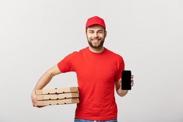 Wall Mural - Pizza delivery man holding a mobile and pizza boxes over white background.