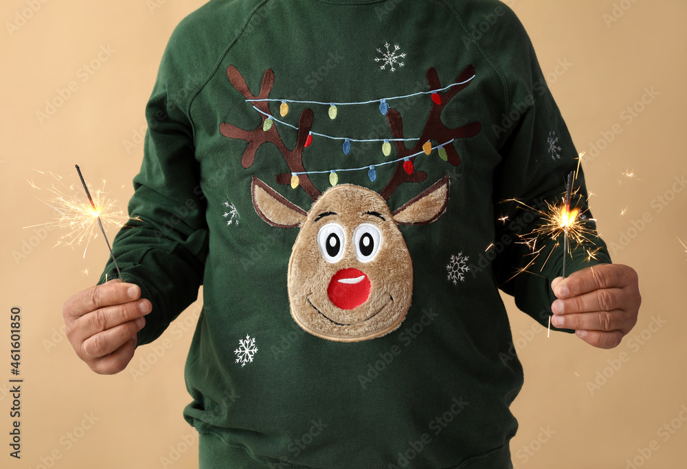 Mature man with Christmas sparklers on color background