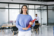 © Marcos - Portrait of young latin businesswoman holding a red folder in meeting with colleagues in modern office in Mexico