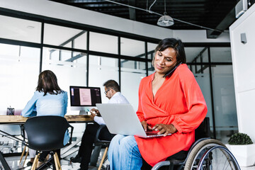 Wall Mural - Mexican transgender businesswoman in wheelchair making phone call while working on computer at work in Mexico