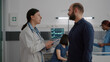 © DC Studio - Practitioner woman doctor discussing medical expertise with worried father during recovery examination in hospital ward. African american nurse explaining sickness therapy treatment to mother