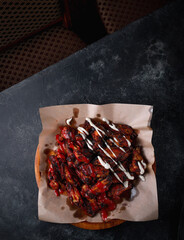 Wall Mural - Spicy breaded chicken wings with tomato and cream sauce on a dark table