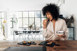 © Daniel - Young african american woman eating breakfast in beautiful bright kitchen loft