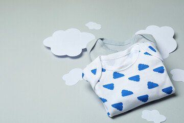 Wall Mural - Baby clothes and decorative clouds on light gray background