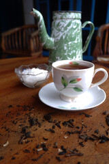 Vertical closeup shot of a cup and saucer with tea and a bowl of sugar