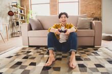 Photo Of Funny Funky Excited Guy Hold Controller Play Console Video Game Sit Floor Wear Yellow Shirt Home Indoors