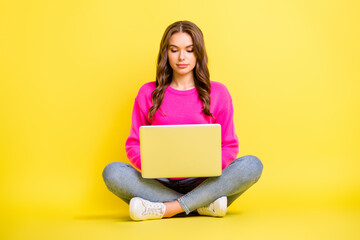 Sticker - Full size photo of young serious focused girl sit floor with crossed legs working in laptop isolated on yellow color background