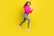 © deagreez - Full length photo of shiny lady dressed pink pullover walking jumping high typing modern device isolated yellow color background