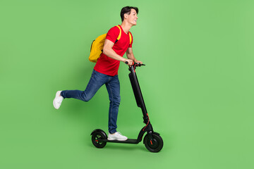 Poster - Full length profile side photo of young guy happy smile ride eco scooter fast tourist hold bag isolated over green color background