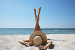 © New Africa - Woman with straw hat lying on sandy beach near sea