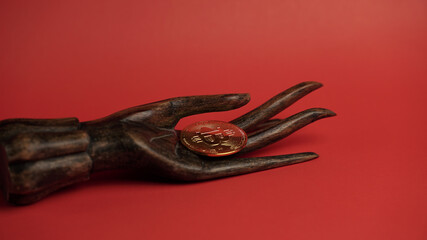 Wall Mural - Hand sculpture holding a Bitcoin coin on a red background