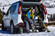 © phpetrunina14 - woman changing boots to ski sitting in car trunk. sunny day