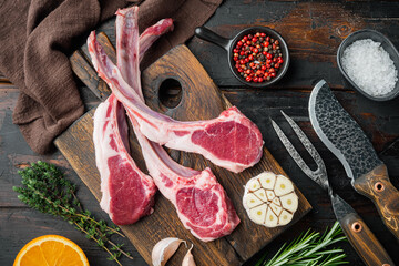 Raw lamb chops or mutton cuts, with ingredients carrot orange, herbs, on old dark  wooden table background, top view flat lay