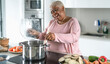 © Alessandro Biascioli - Happy senior woman having fun preparing lunch in modern kitchen - Hispanic Mother cooking for the family at home