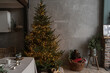 © Floral Deco - Modern home interior design concept. Comfortable cozy living room decorated with Christmas tree with gifts, table, grey walls, toys. Christmas, New Year celebration decorations.