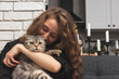 © Igor Barilo - Happy young woman hugging her Scottish fold cat, pet love concept.