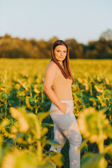 Poster - Vertical shot of a white Caucasian woman posing for a picture in a sunflower field