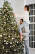 © Olena Bloshchynska - Couple decorating Christmas tree. Woman sitting on the shoulders of man.