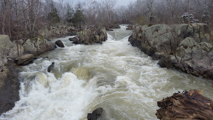 Wall Mural - Beautiful clear river flows between large stones during the day surrounded by trees