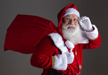 Santa Claus In Eyeglasses Is Looking At Camera And Smiling, On Gray Background