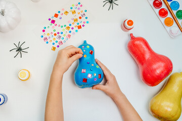 Kids hands holding decorated pumpkins on the table