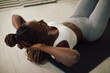 African American athletic woman exercises sit-ups while working out at home.