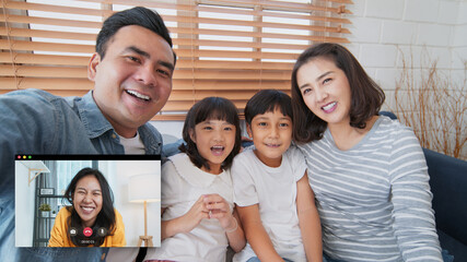 Young Asian family on video call, online remote meeting at home, look at camera. Internet communication information technology, people connection lifestyle, or coronavirus social distancing concept