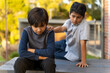 © Anjuman - Friends caring concept. Resolving conflict with angry child. Two young boys together. Hand on shoulder. Kids communication concept.