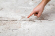 Young adult man hand finger pointing to cracked concrete floor. Building problem and solution concept. Closeup.