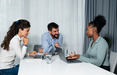 Wall Mural - Three young business people work as colleagues in a modern office sitting at the desk at a development company