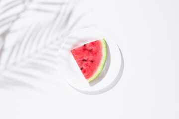 Sticker - Slice of watermelon on a white plate on a white table. Top view, flat lay