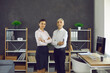 © Studio Romantic - Serious young woman and elderly man in white shirts standing arms folded in modern office. Portrait of two confident people, business professionals, company owners and co founders with arms crossed