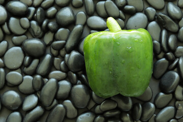 Wall Mural - Top view one green bell pepper on black stone that has smooth glossy skin and round edge.