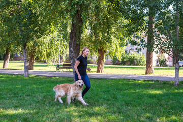 Wall Mural - young blonde woman with her dog retriever in the park