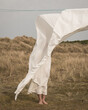 © Milou Dirks - girl standing outdoors in white dress behind sheet on washline