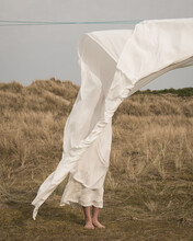 Girl Standing Outdoors In White Dress Behind Sheet On Washline