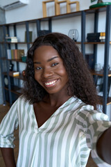 young happy black african woman holding phone looking at mobile vertical camera streaming vlog, taki