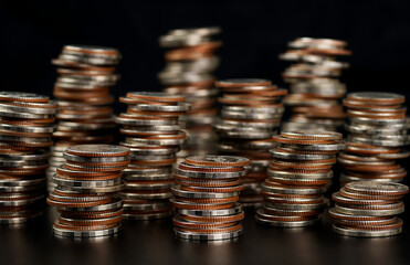 Lots of stacked coins on a black background.	